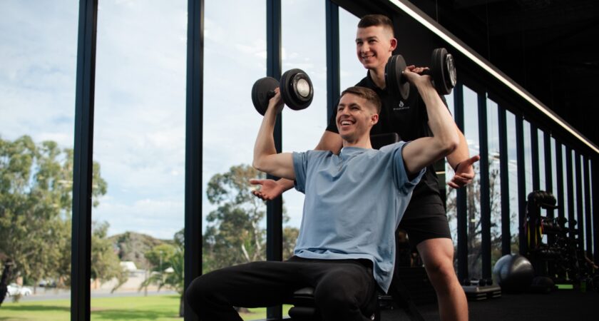 Photo of Tristan from Naru Fitness helping a client at a gym.